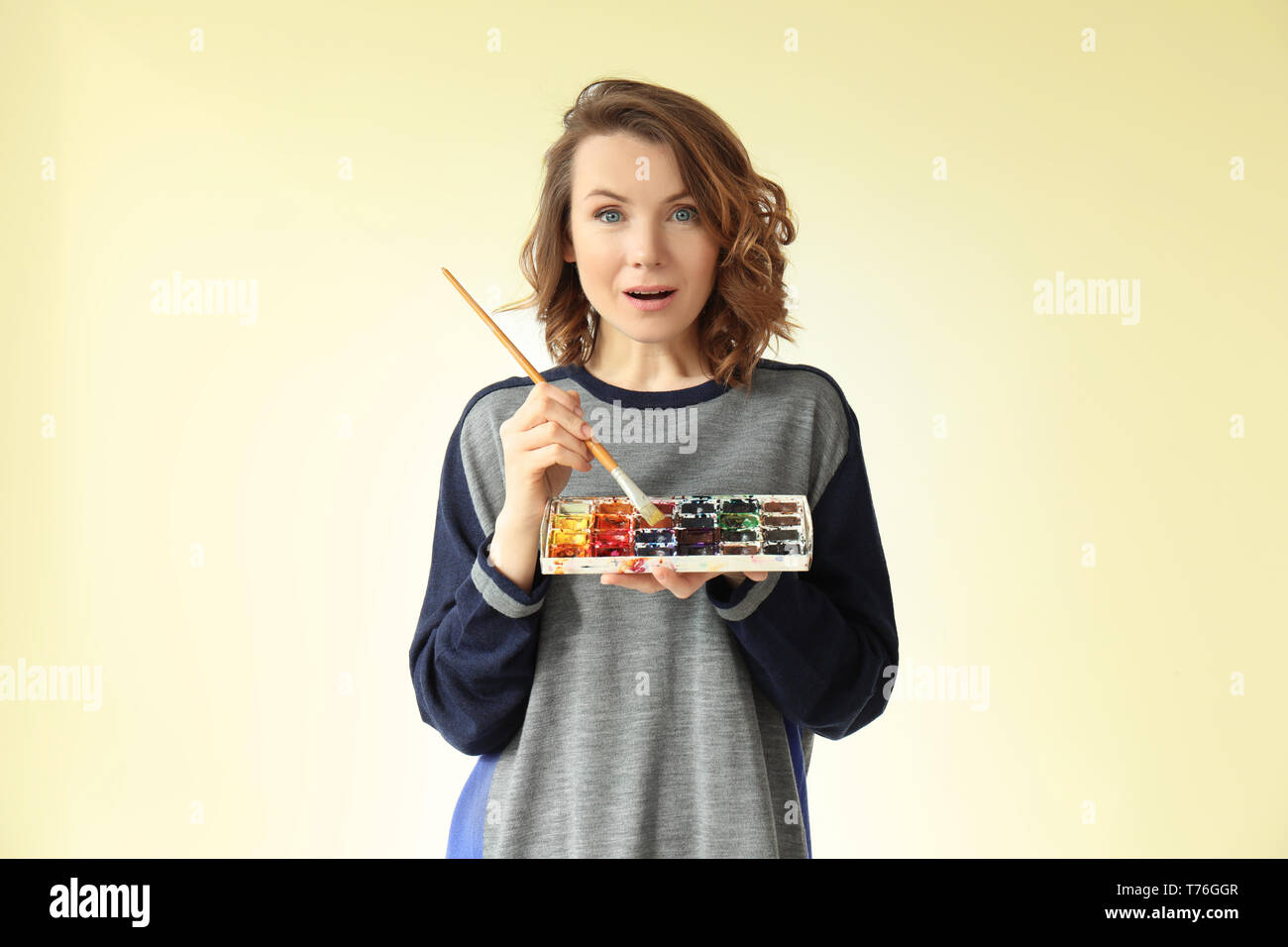 Female artist with brush and paint palette on light background Stock ...