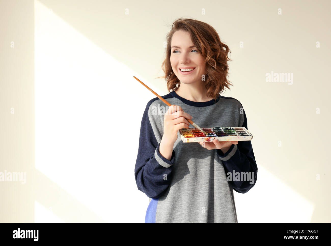 Female artist with brush and paint palette on light background Stock ...