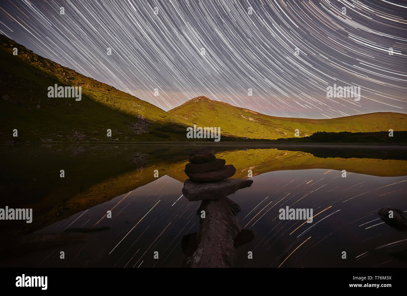 Magic night landscape with mountains, lake and amazing starry sky, star trails in the night sky, pyramid of stones. Chornogora, Nesamovyte lake. Carpa Stock Photo