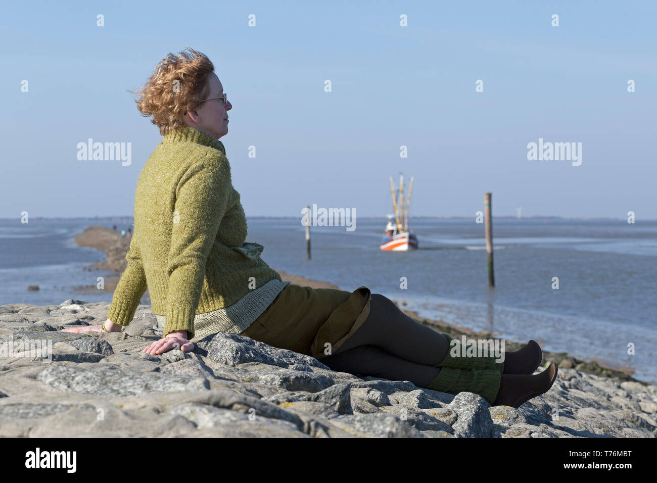 woman watching arriving fishing boats, Neuharlingersiel, East Friesland, Lower Saxony, Germany Stock Photo