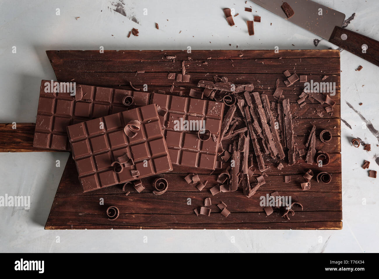 Wooden board with pieces of chocolate on light background Stock Photo ...