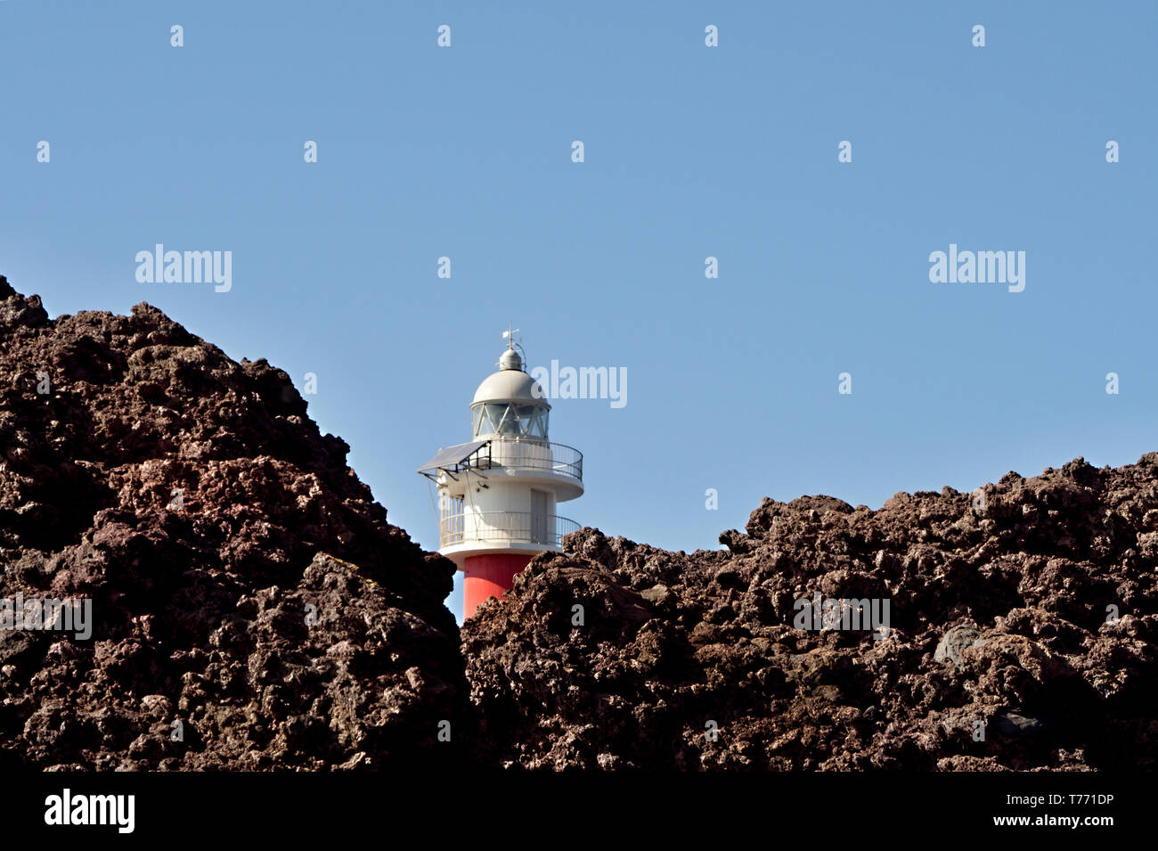 The red-white lighthouse of the point of the Teno Mountains stands in a volcanic landscape, the 'Punta de Teno'  Loose volcanic rock Stock Photo