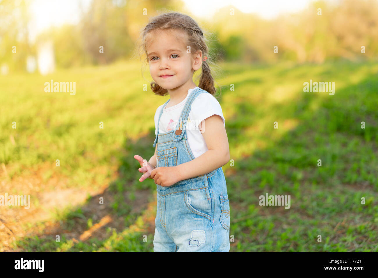 Summer season. Little Caucasian girl walks on nature dressed in denim