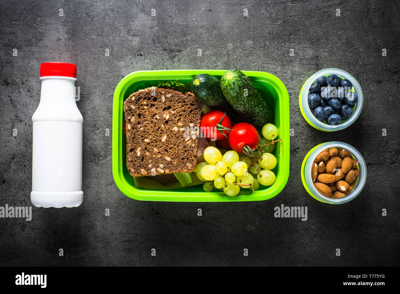 Lunch box with sandwich, vegetables, banana, yogurt, nuts and ber Stock
