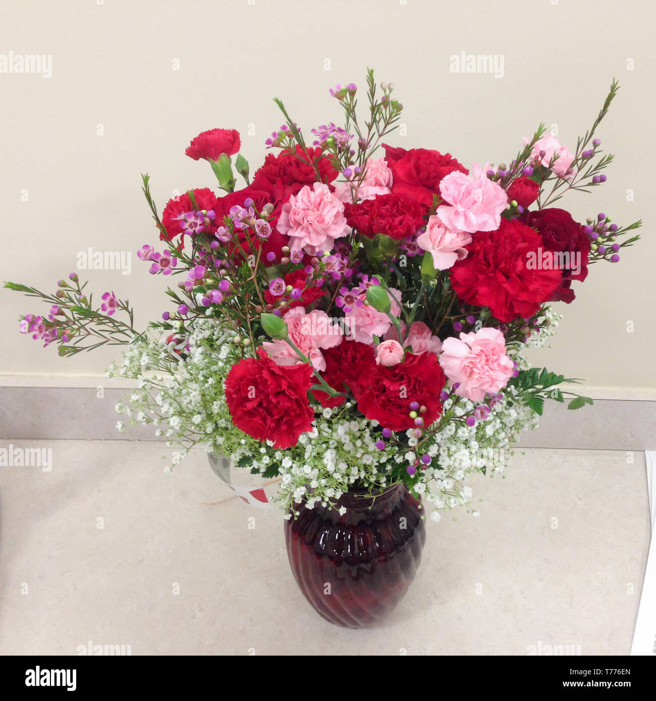 Flower bouquet with red roses in a vase on a desk Stock Photo