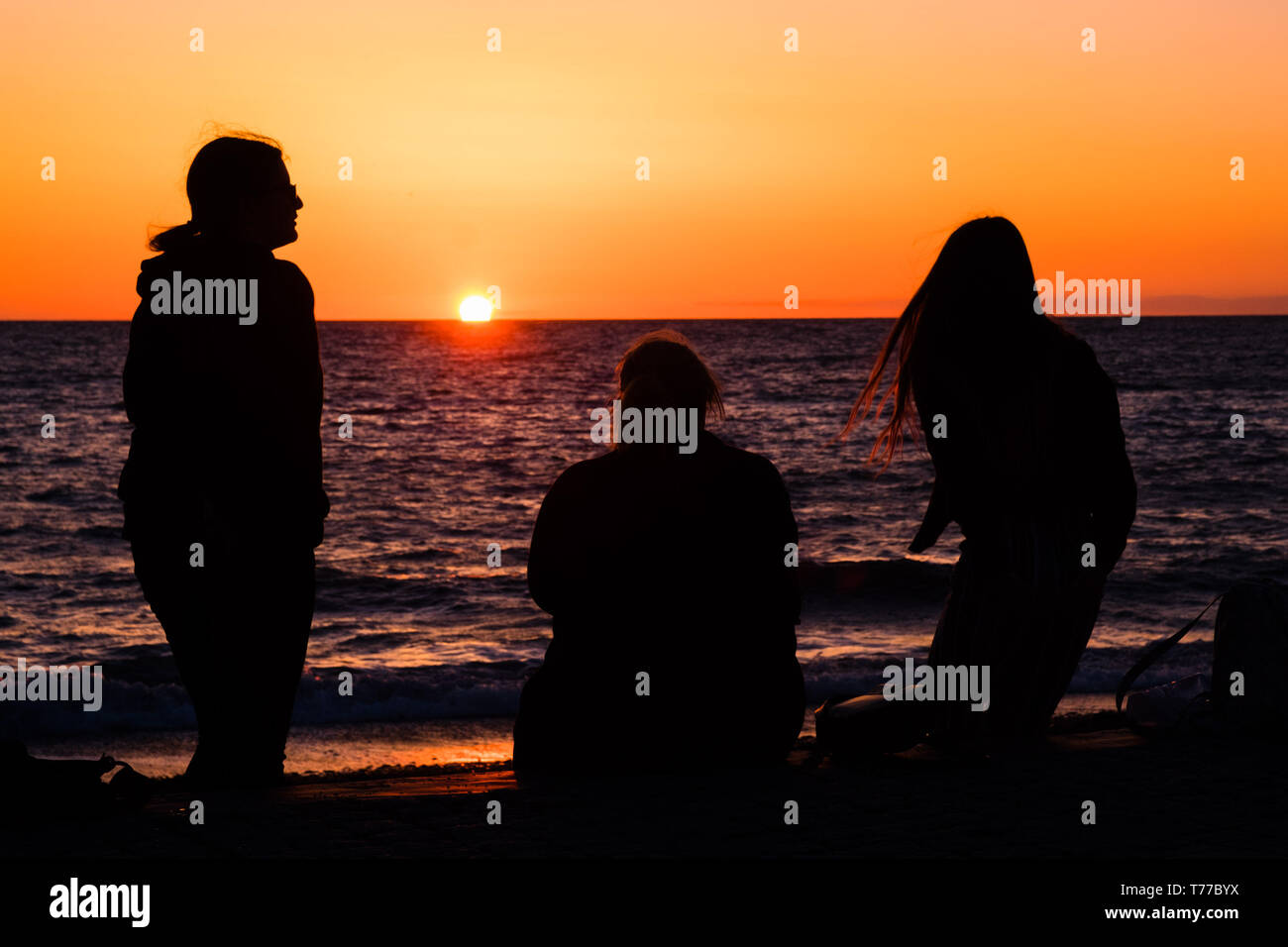 Aberystwyth, UK. 4th May, 2019.   UK Weather: People watching a glorious sunset over Cardigan Bay in Aberystwyth, at the end of a day of bright sunshine, blue skies but a bitingly cold northerly wind, on the Satrurday evening of the early May Bank Holiday weekend  photo credit Keith Morris / Alamy Live News Stock Photo