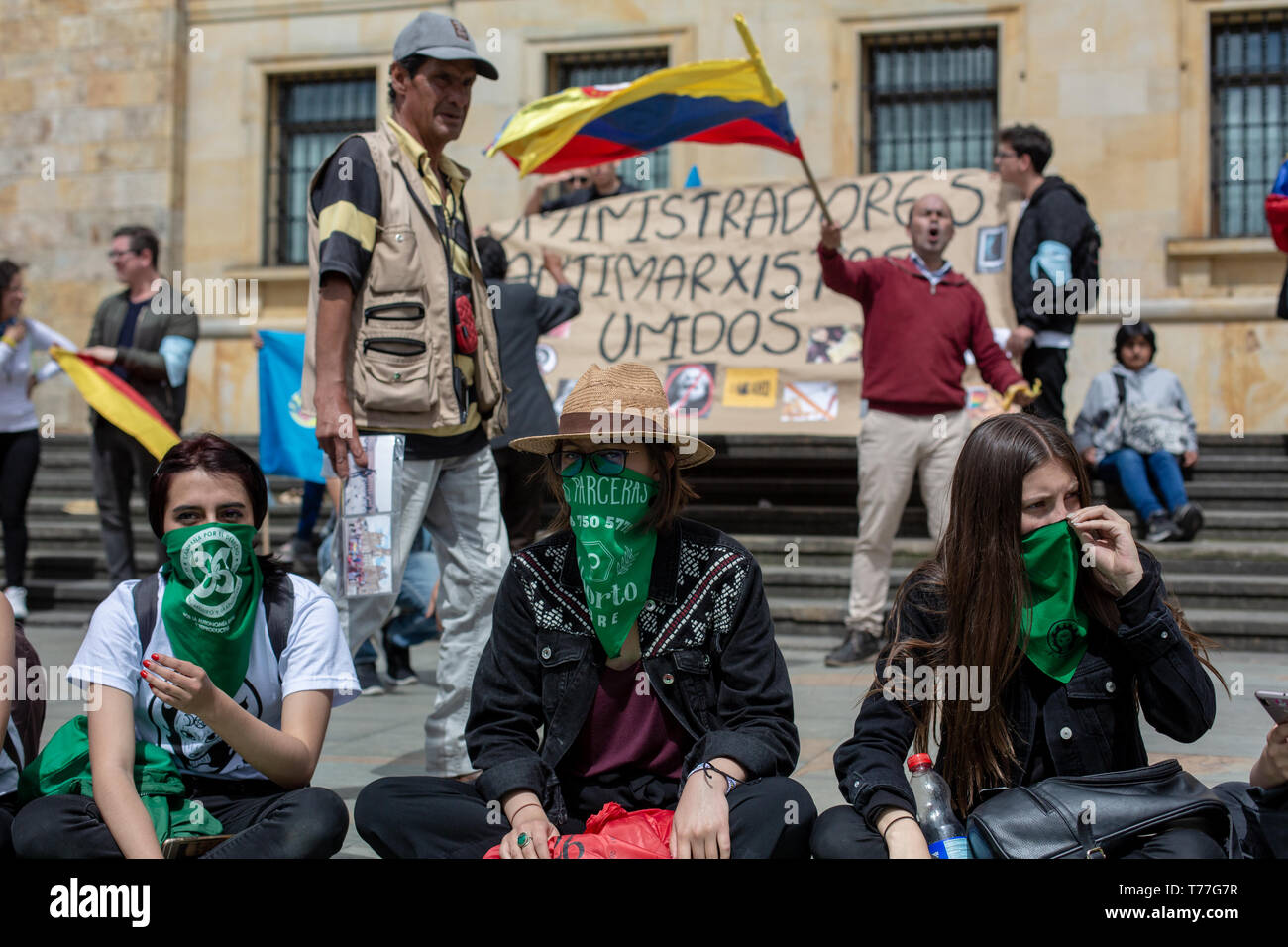 Bogota, Colombia. 04th May, 2019. Feminists with green scarf covering their faces sitting front of the Pro-Life protesters as an act of rebellion against them during the 'Unidos por la vida' (United for Life) Pro life rally in Bogota.  Under the slogan 'I choose the two lives' around 500 people demonstrated for the maintenance of traditional family values, against abortion and the killing of social leaders in the country. Catholic and right wing political groups joined the call of the 'United for Life' Platform (Unidos por la Vida) a widely spread organization in Colombia. Credit: SOPA Images  Stock Photo
