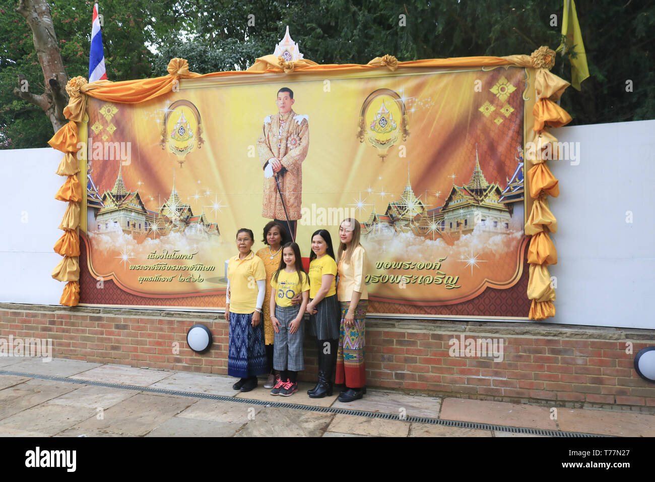 London UK. 5th May 2019. Members of the Thai community wearing the yellow  Royal colours of the Thai monarchy pose in front of a giant poster of the newly crowned monarch  King Rama X of Thailand, Maha Vajiralongkorn  at the Wat Buddhapadipa Buddhist temple in Wimbledon to celebrate his coronation Credit: amer ghazzal/Alamy Live New Stock Photo