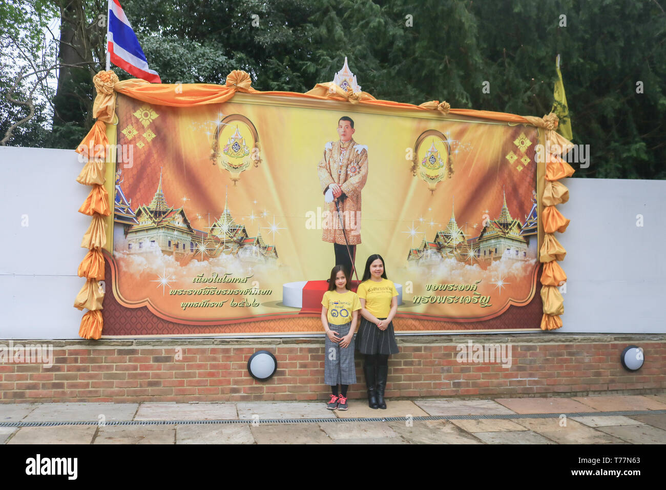 London UK. 5th May 2019. Members of the Thai community wearing the yellow  royal colours of the Thai monarchy pose in front of a giant poster of the newly crowned monarch  King Rama X of Thailand, Maha Vajiralongkorn  at the Wat Buddhapadipa Buddhist temple in Wimbledon to celebrate his coronation Credit: amer ghazzal/Alamy Live New Stock Photo
