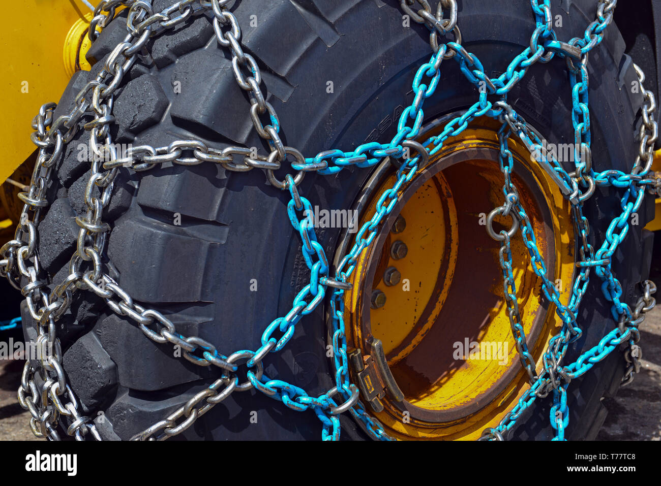 Tire chains for better traction in snow and ice travel on large commercial rubber tire of heavy