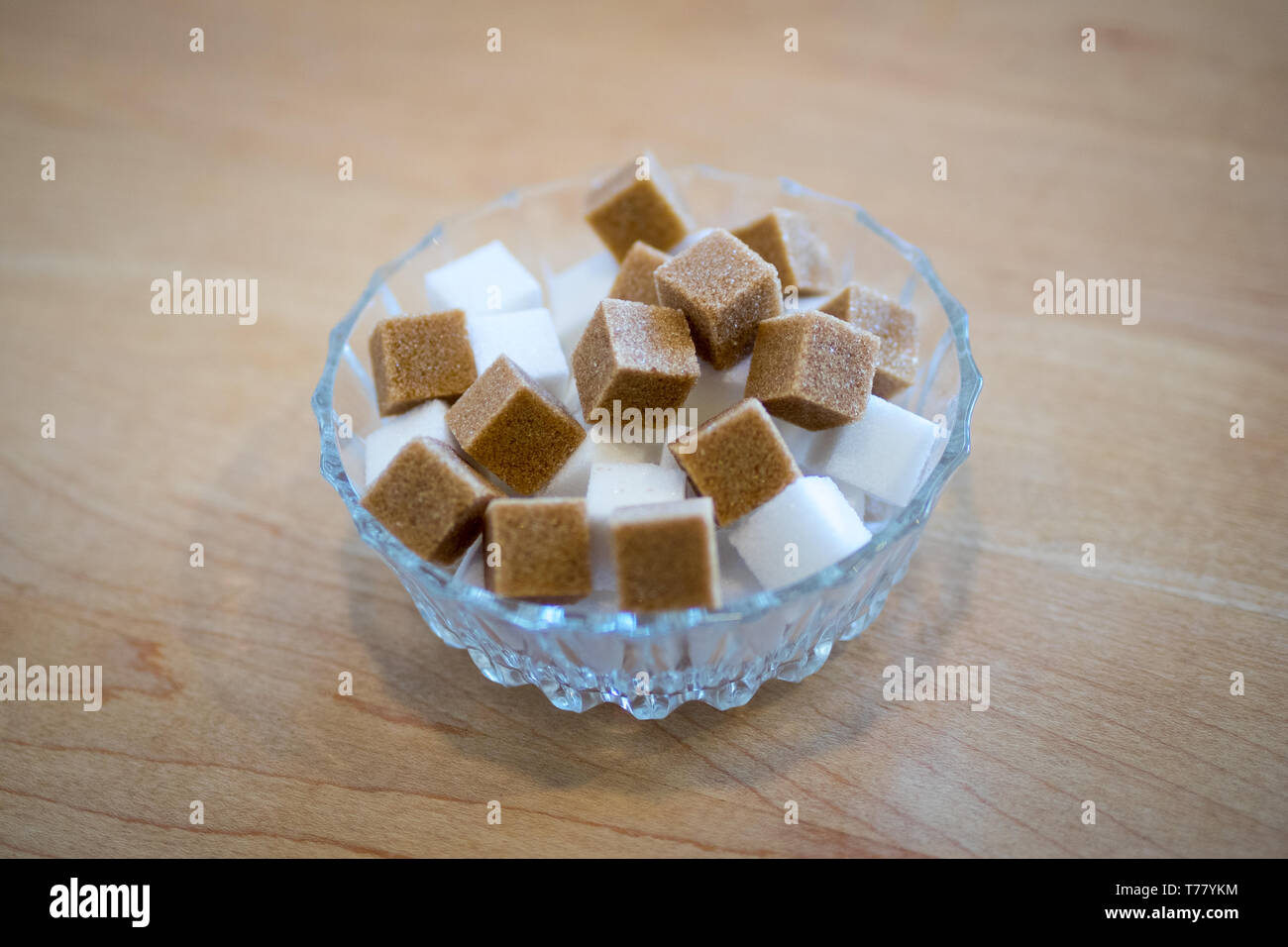 Brown sugar cubes and white sugar cubes in a glass bowl. Stock Photo