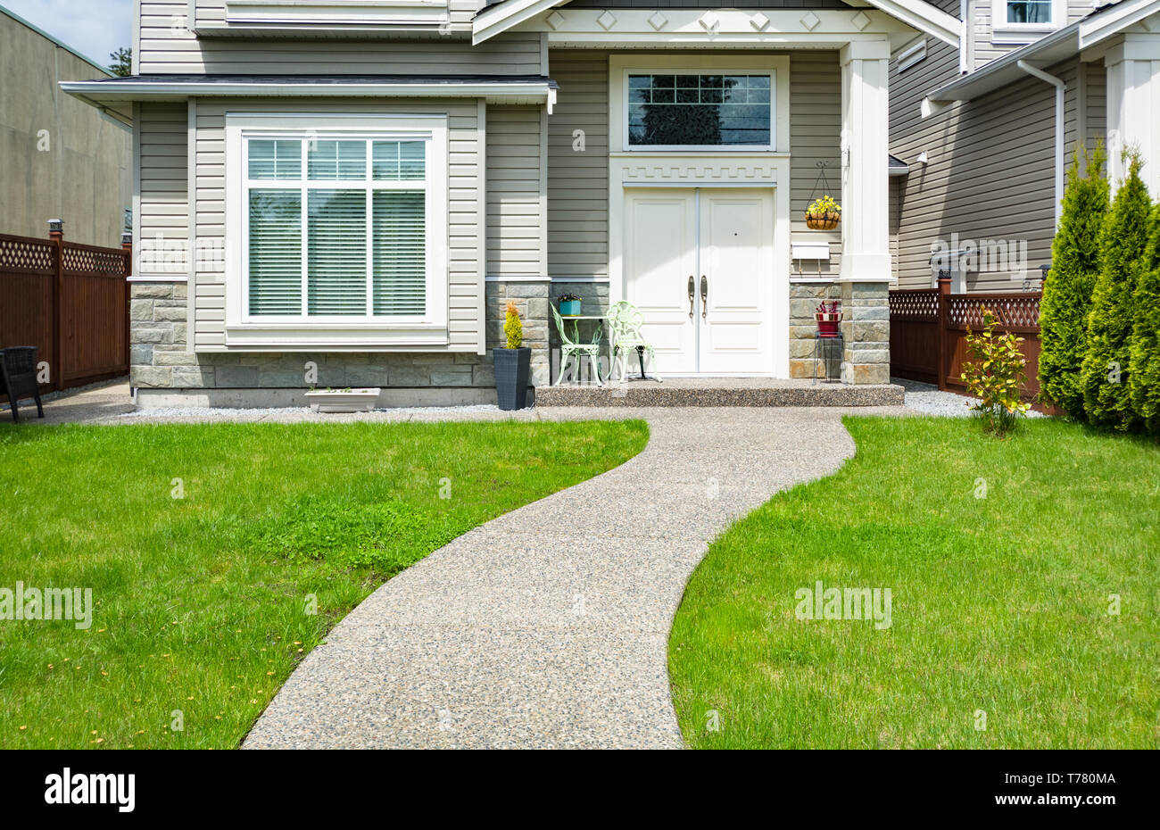 Curved concrete pathway over green lawn to the main entrance of small