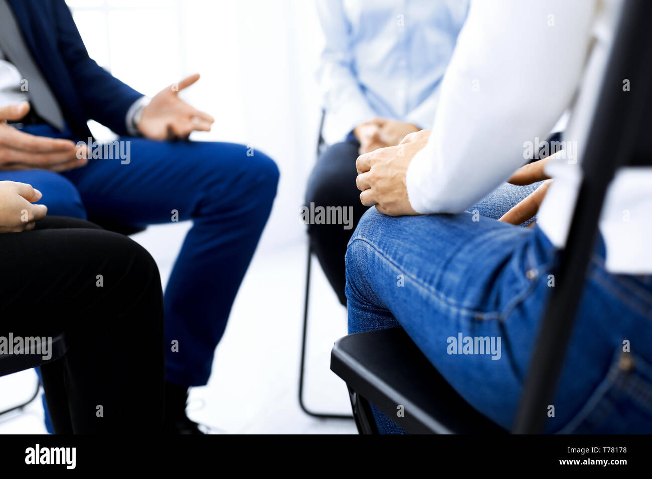 Group of people sitting in a circle during therapy. Meeting of business team participating in training. Stock Photo