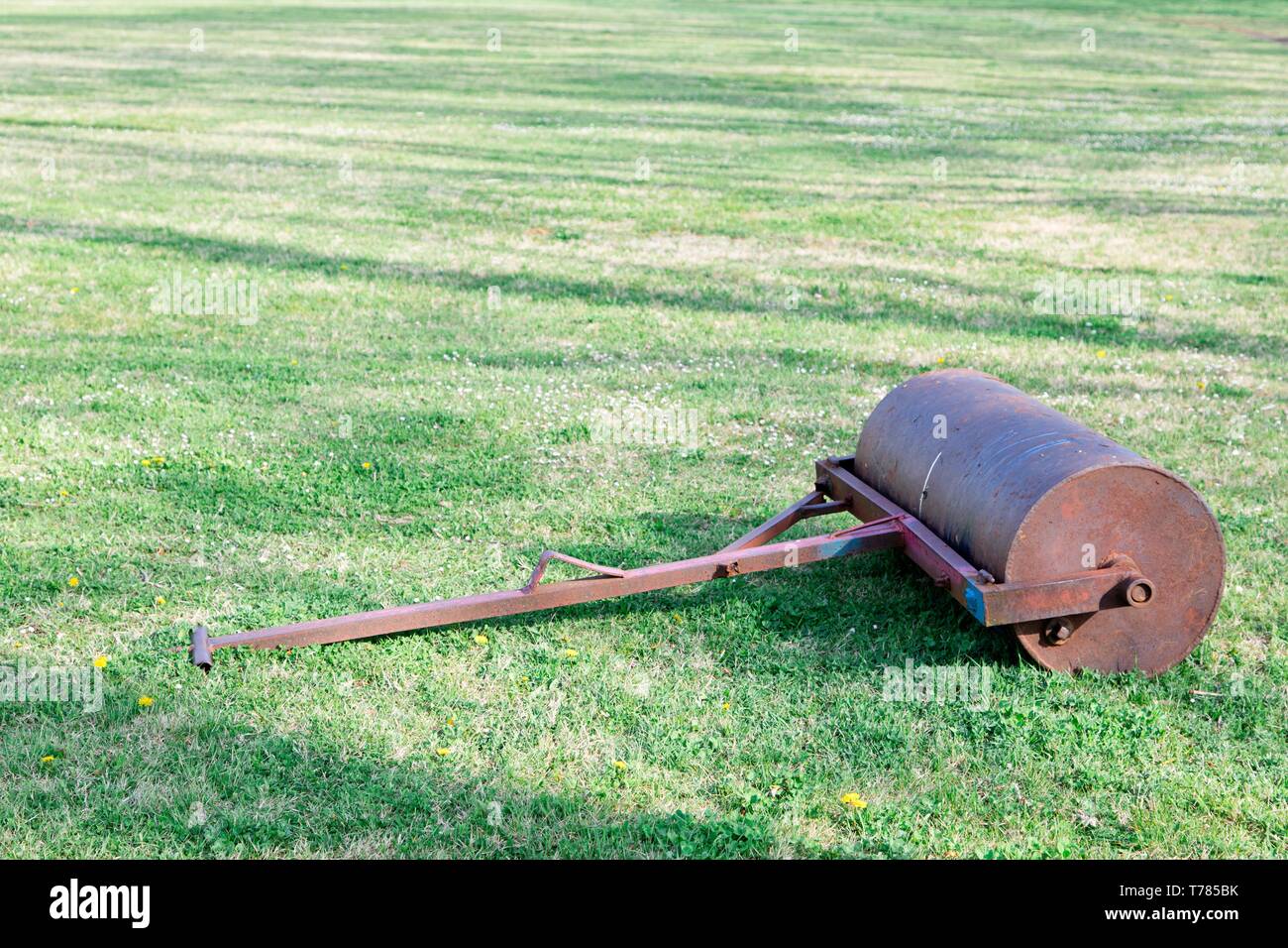 Steel old grass roller on grass yard - rusty tool Stock Photo