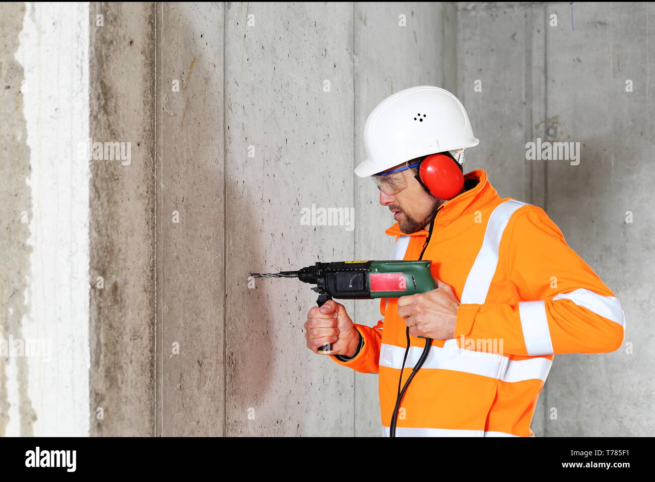 A Worker man drilling in concrete on a construction site Stock Photo
