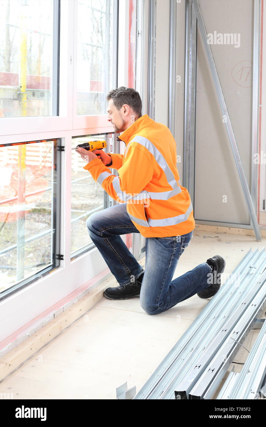 A Worker Man installing a wooden window on construction site Stock Photo