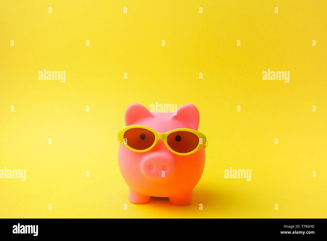 Pink piggy bank with sunglasses on yellow background Stock Photo - Alamy