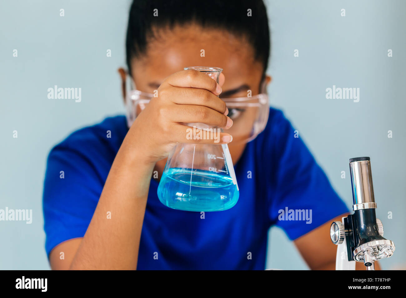 Young African American mixed kid testing chemistry lab experiment and