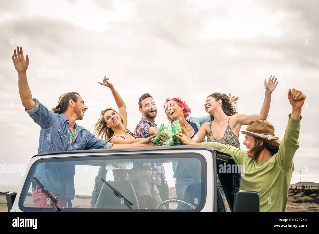 Group of happy friends cheering with beer in convertible car - Young people having fun drinking and making party during their road trip Stock Photo
