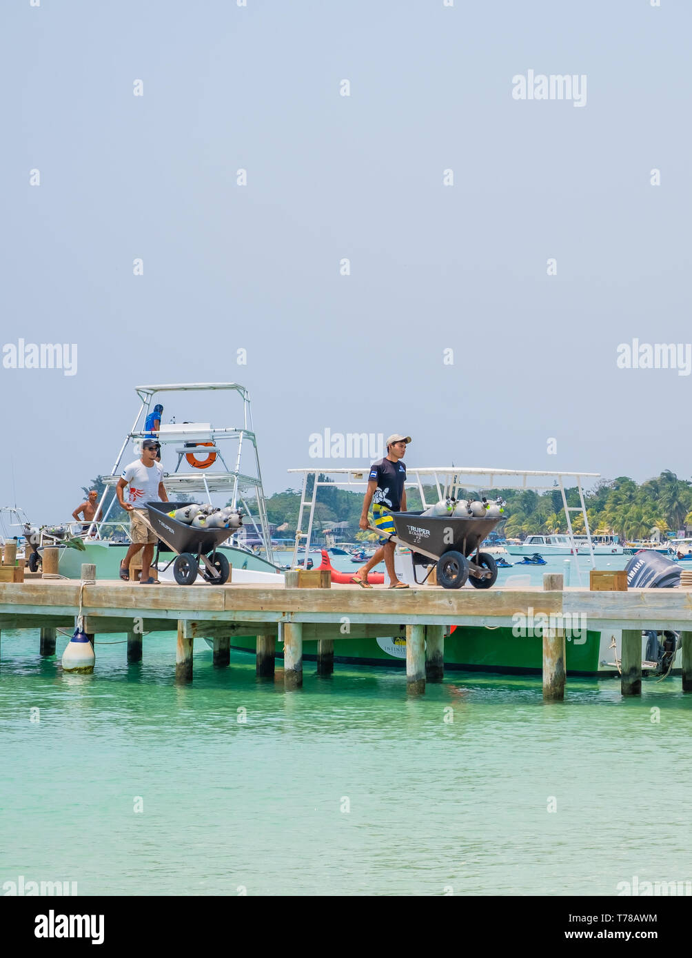 Workers remove depleted SCUBA tanks from a tourist dive boat at West Bay Beach Roatan Honduras. Stock Photo