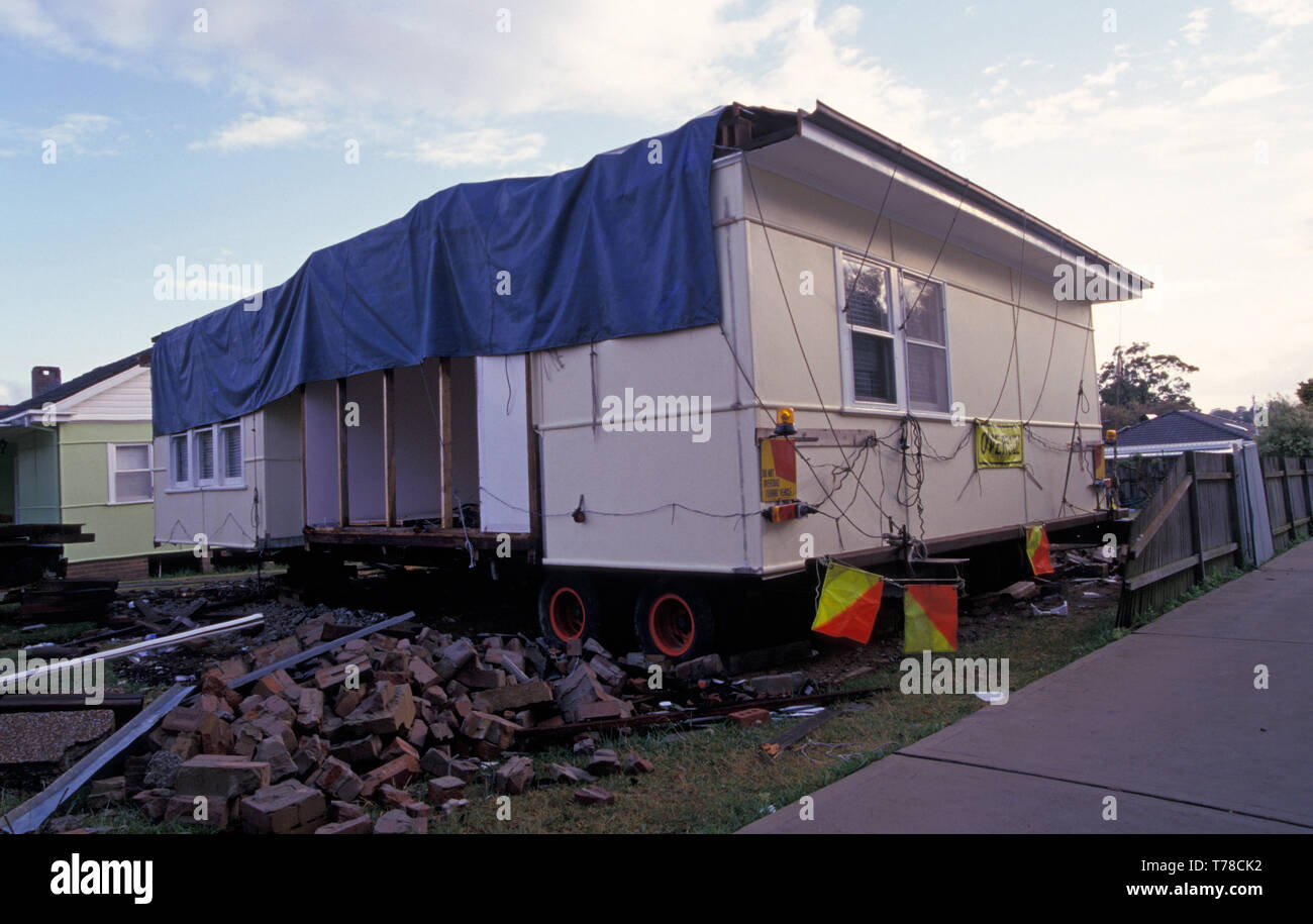 AN OLD FIBRO HOME IS MADE READY FOR REMOVAL BY SEMI FOR DEMOLISHING. SIGNS ARE ATTACHED ADVISING OVERSIZED LOAD, SUBURBAN SYDNEY, NEW SOUTH WALES, Stock Photo