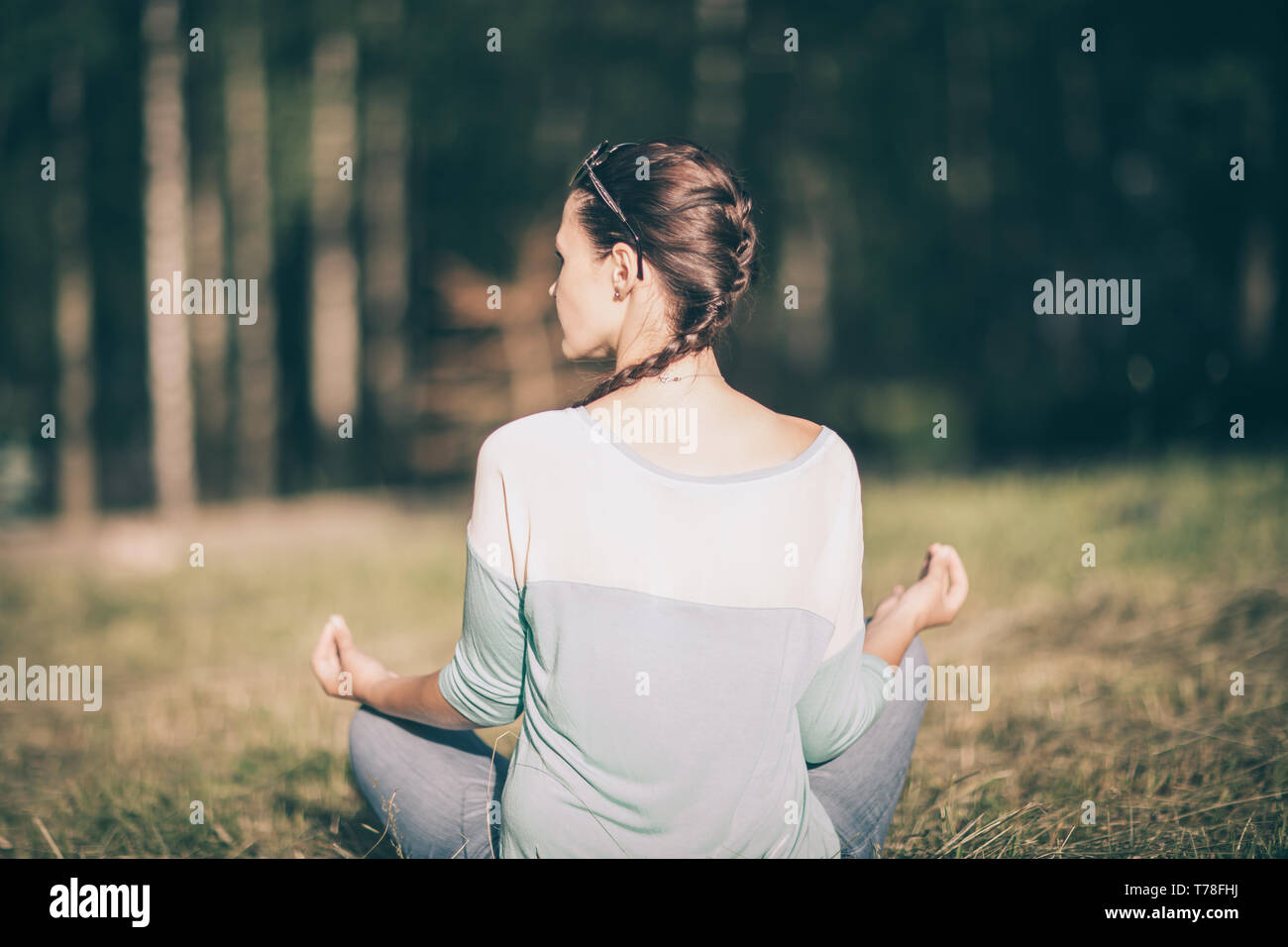 rear view. young woman meditating in Lotus position in Sunny Park. the ...
