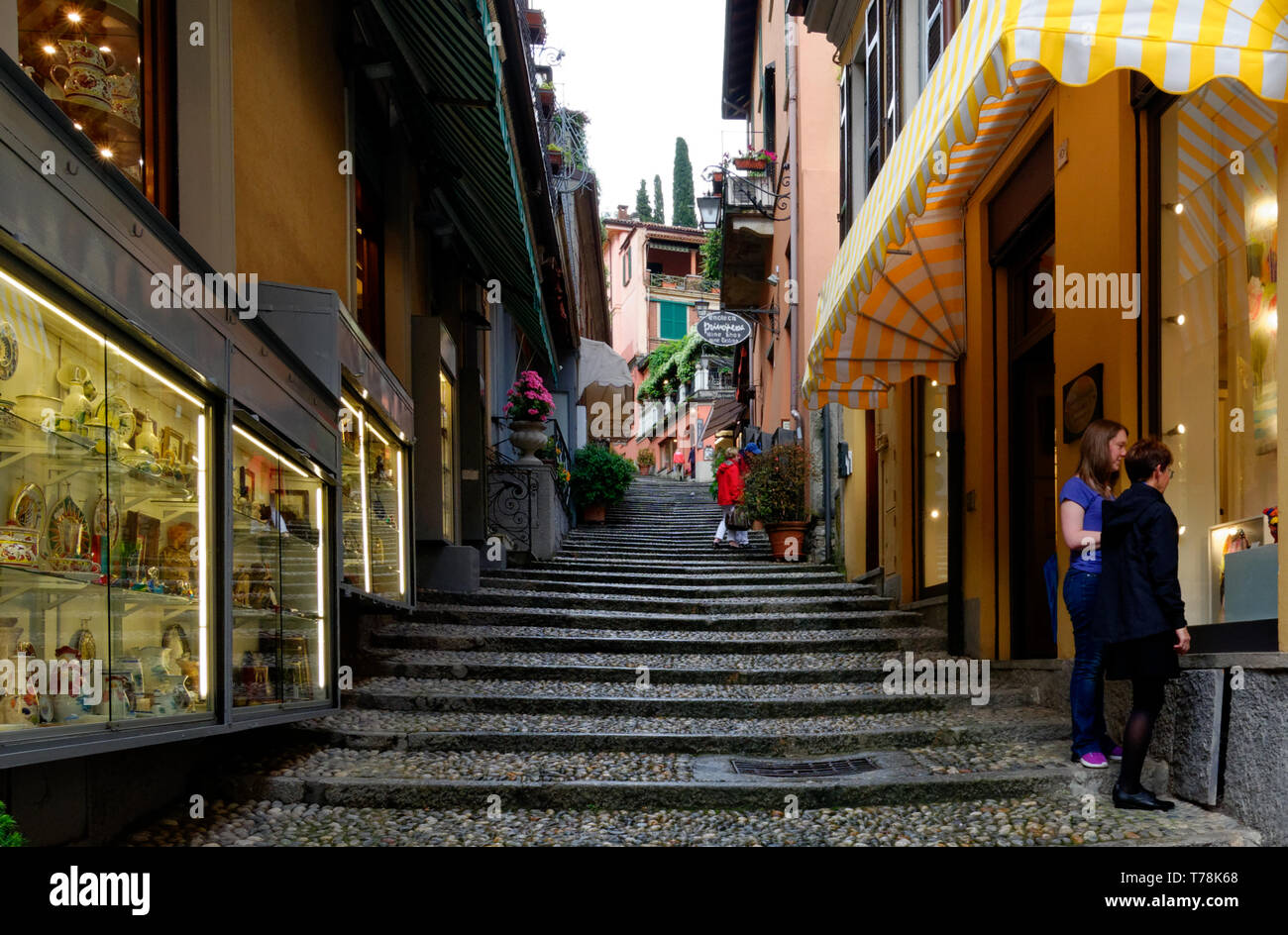 Tourists on cobbled stairs admiring the wares in high end shops in an alley in Bellagio, Italy Stock Photo