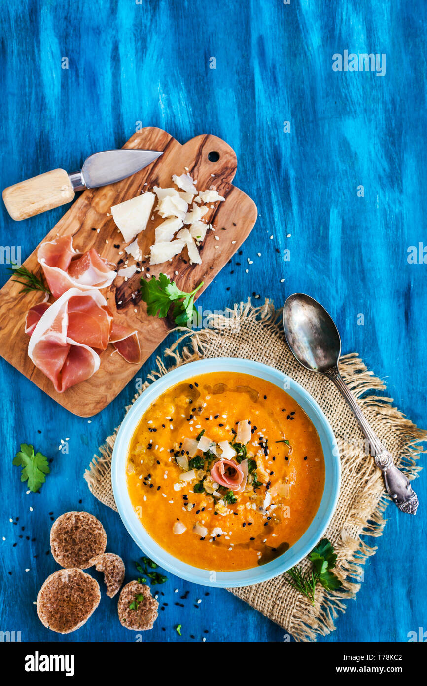 Pumpkin cream soup bowl, served with sesame,  prosciutto, parmesan cheese, olive oil, balsamic and herbs Stock Photo