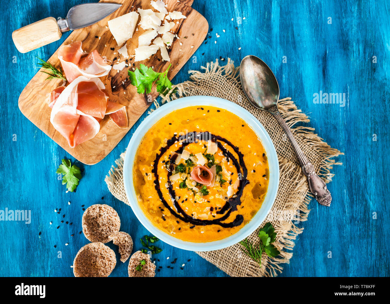 Pumpkin cream soup bowl, served with sesame,  prosciutto, parmesan cheese, olive oil, balsamic and herbs Stock Photo