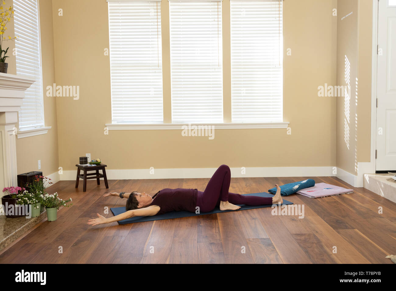 Yoga pose on back arms overhead one knee bent Stock Photo