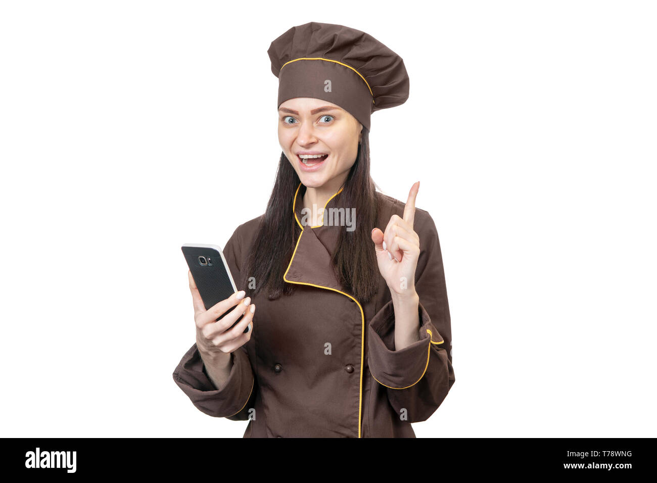 Portrait of handsome smiling chef raising his index finger upwards with a phone in his hand isolated on white background Stock Photo