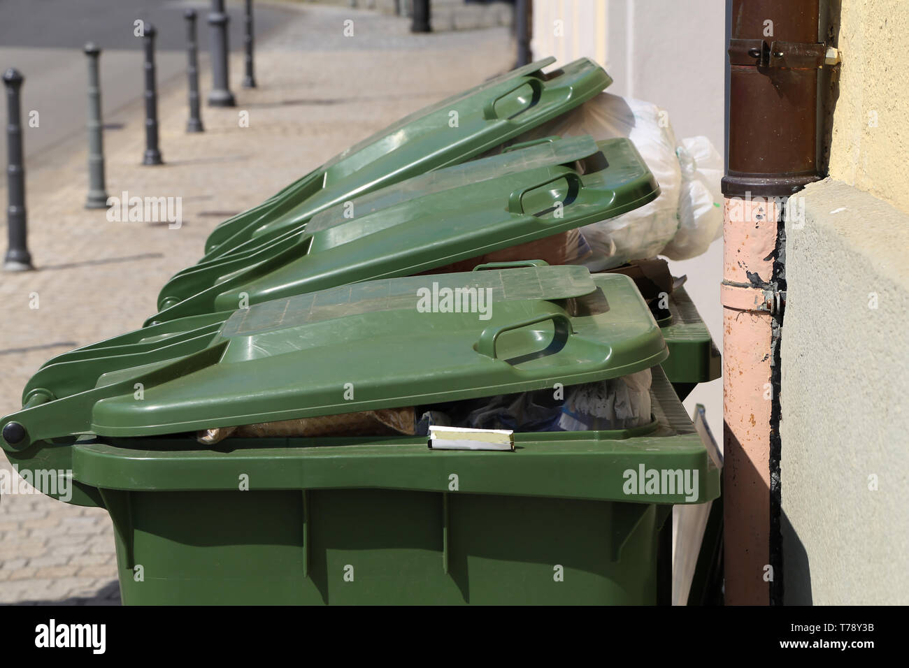 Green garbage cans are on the street near the house Stock Photo Alamy