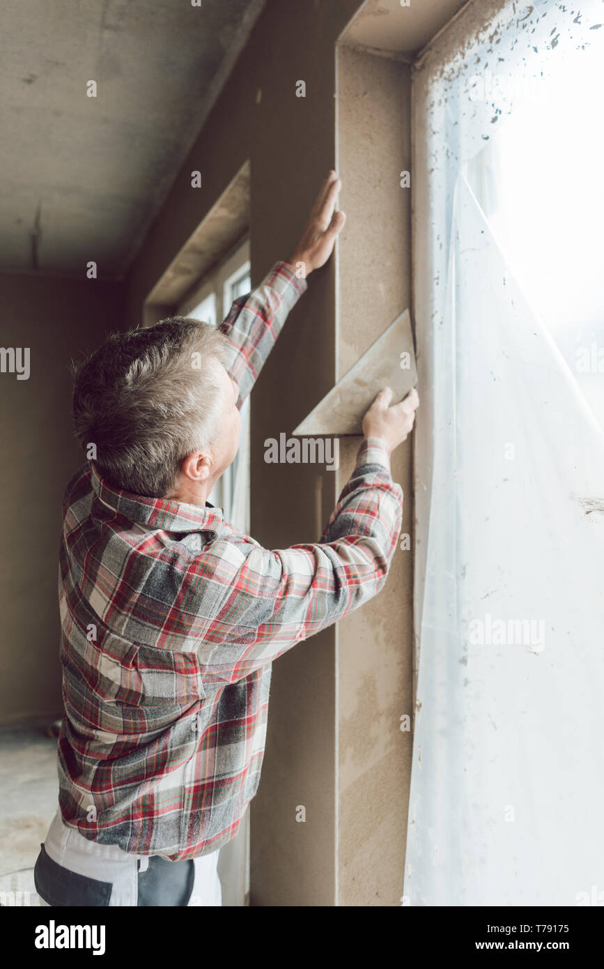 Diligent plasterer working on a window opening Stock Photo