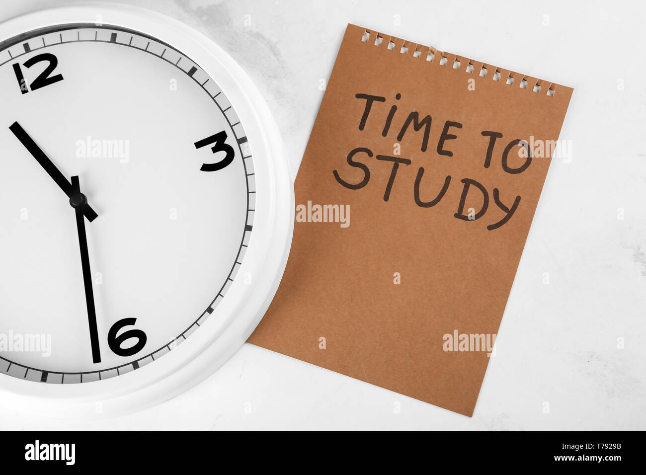 Clock and sheet of paper with inscription TIME TO STUDY on light ...