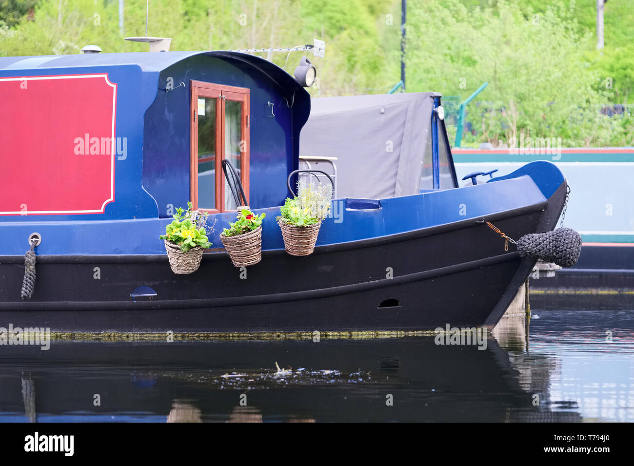 Barge boat on canal showing hanging flower pops Stock Photo