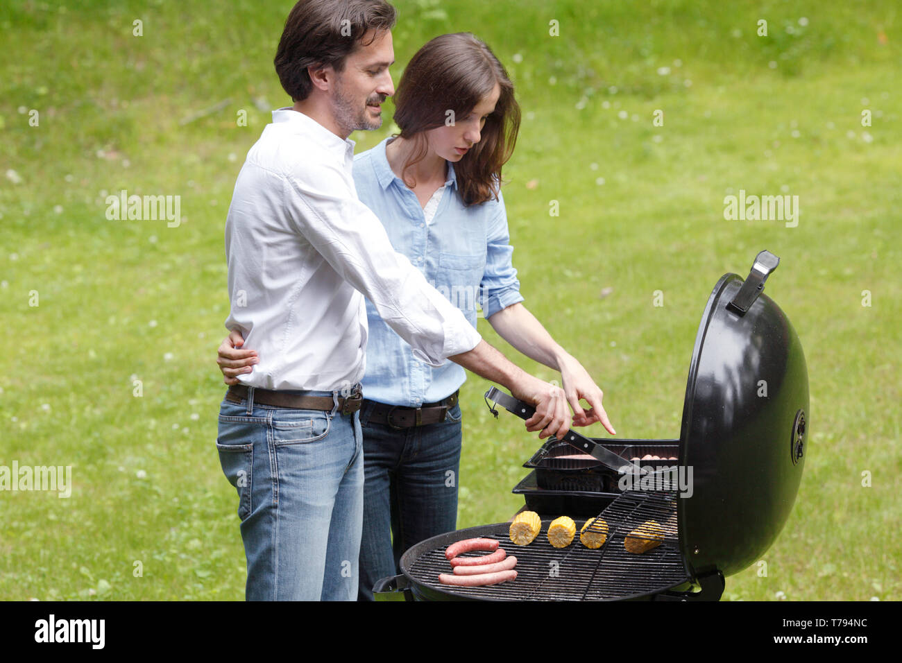 Happy couple cooking food on barbecue Stock Photo - Alamy