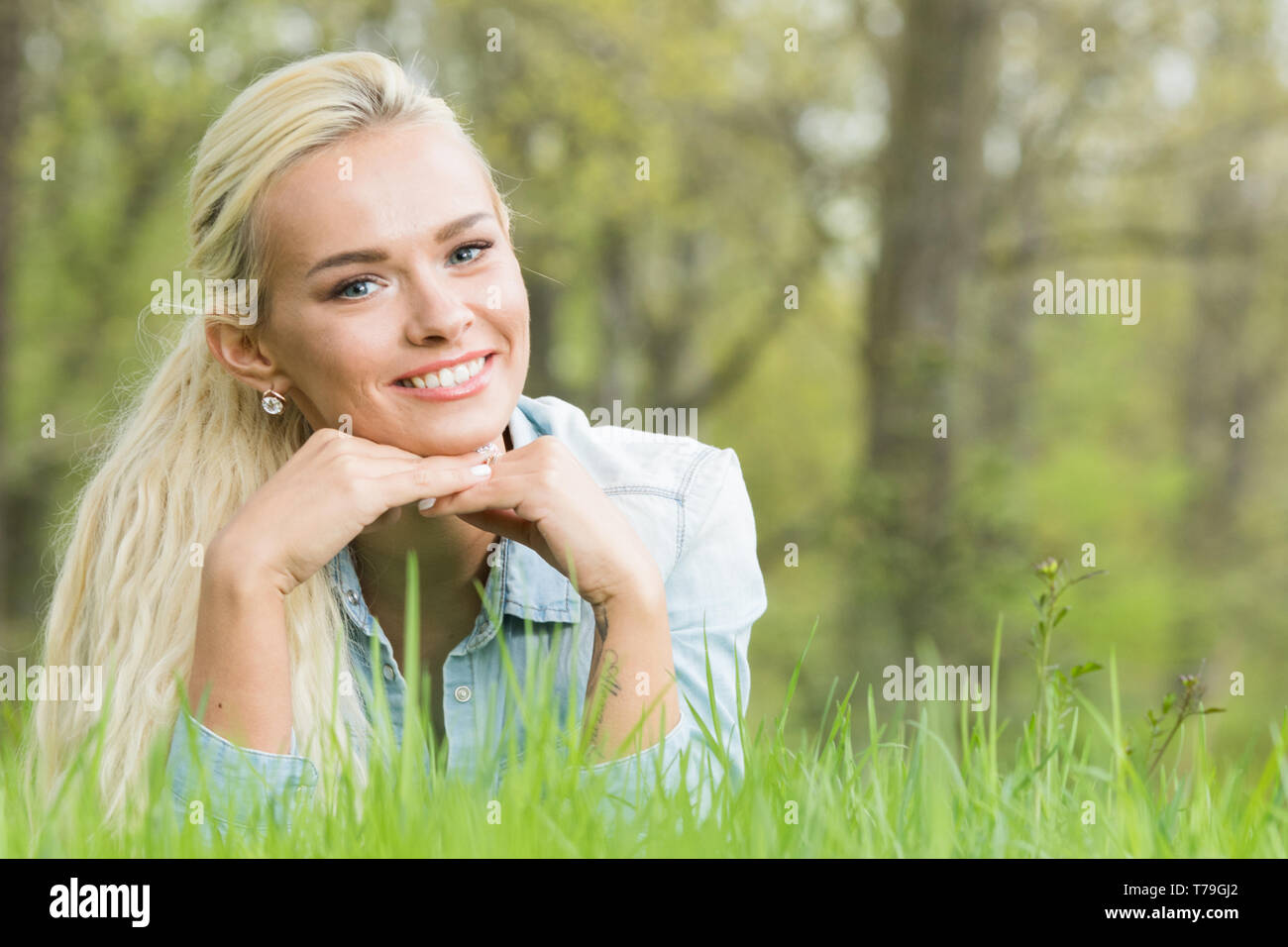 Blonde pretty girl laying on the grass in spring park and smiling Stock ...