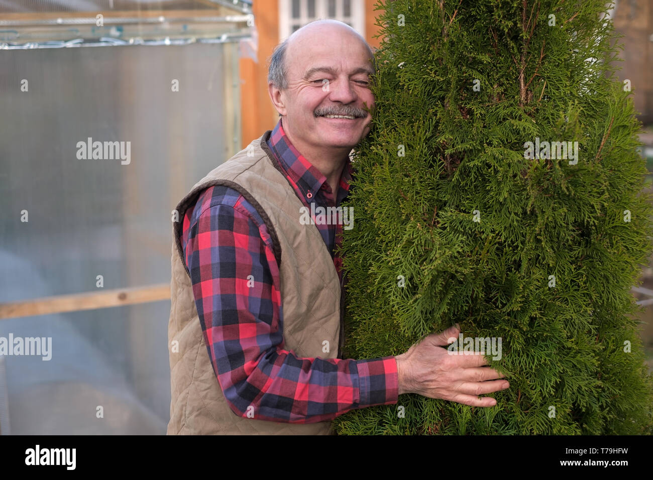 Mature man being proud of his garden hugging his favourite tree Stock Photo