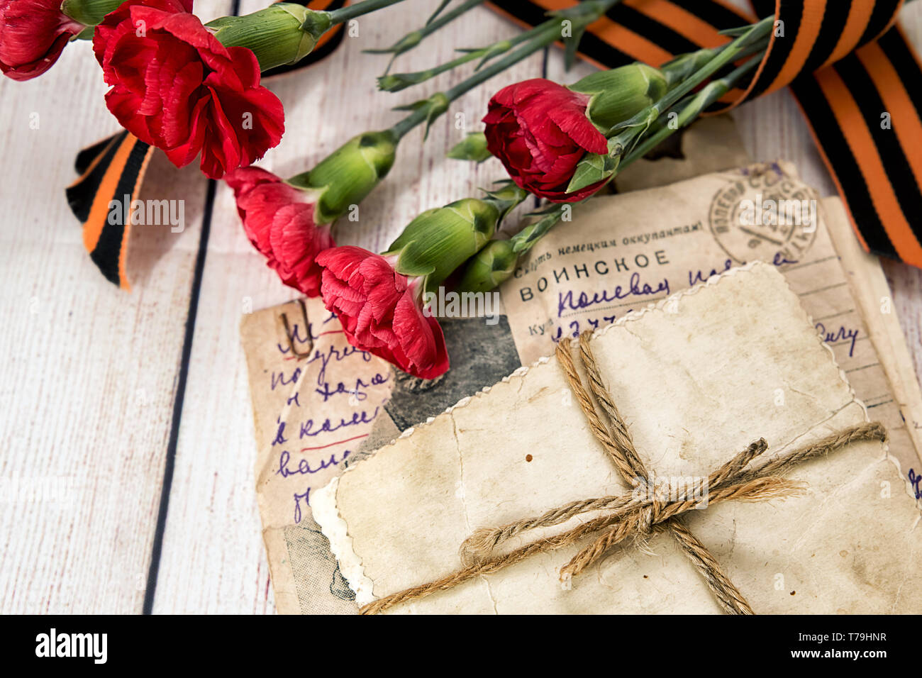 Military letter, old photos, carnations and Gergiev's ribbon. Field mail / old letter is in my personal family archive. Russian translation: Death to  Stock Photo