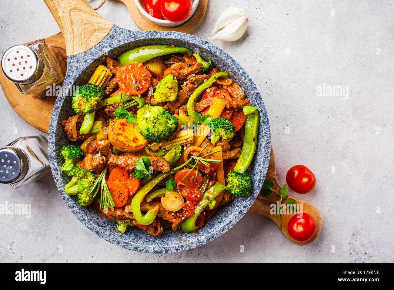 Fried beef stroganoff with potatoes, broccoli, corn, pepper, carrots and sauce in a pan, white background. Stock Photo