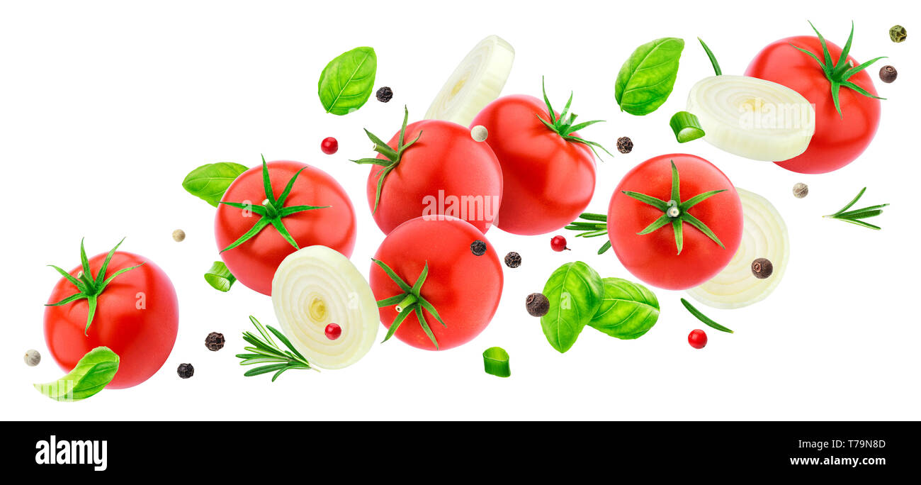 Flying tomatoes salad isolated on white background with clipping path, falling fresh vegetable ingredients: tomato, onion, basil and spices Stock Photo