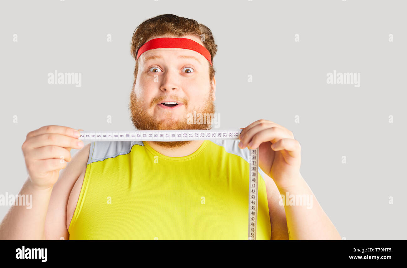 Funny fat man holding a centimeter with funny emotion. Stock Photo