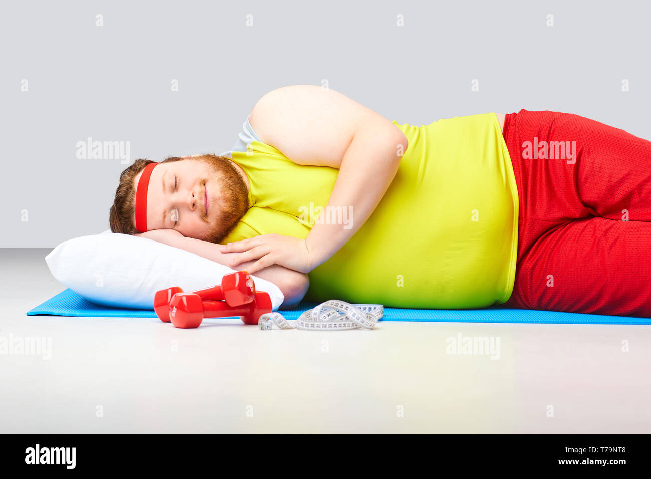 Lazy fat funny man is sleeping on a gray background. Stock Photo