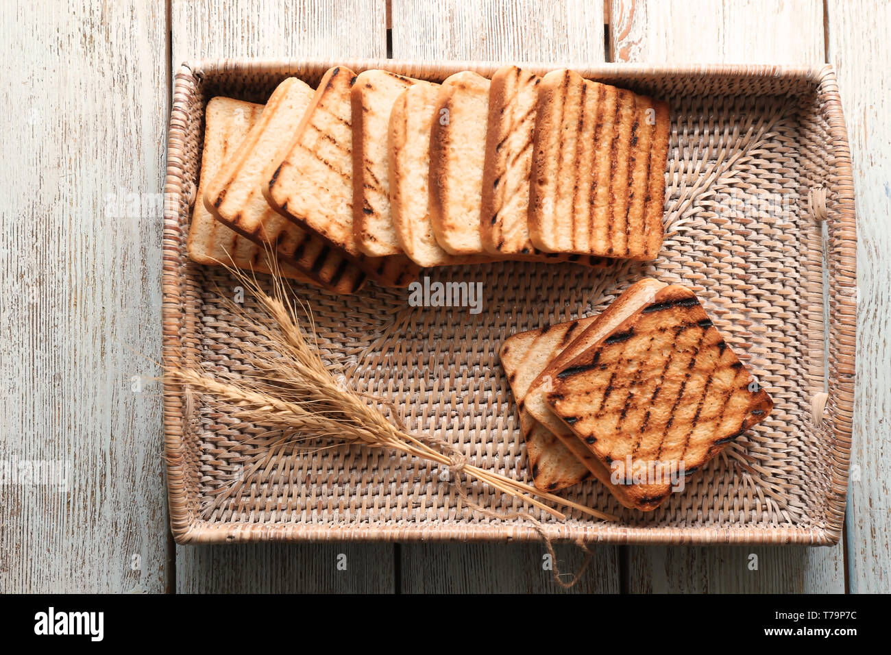 Wicker tray with toasted bread on wooden table Stock Photo