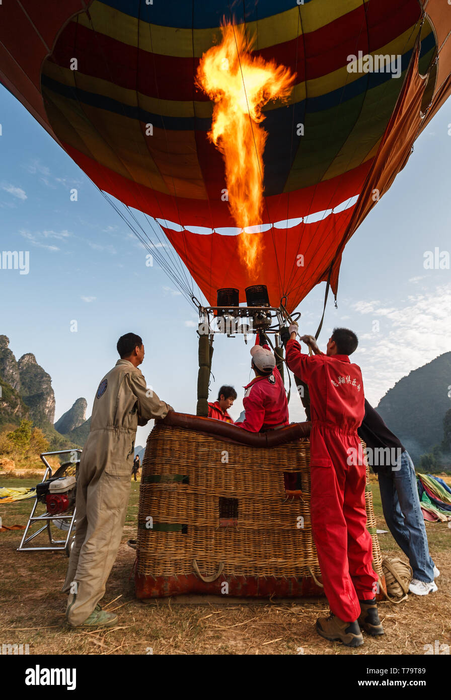 Workers in basket for safety check flame adjustment so people can have a hot air balloon  ride over the Yangshao Valley and mountains Stock Photo