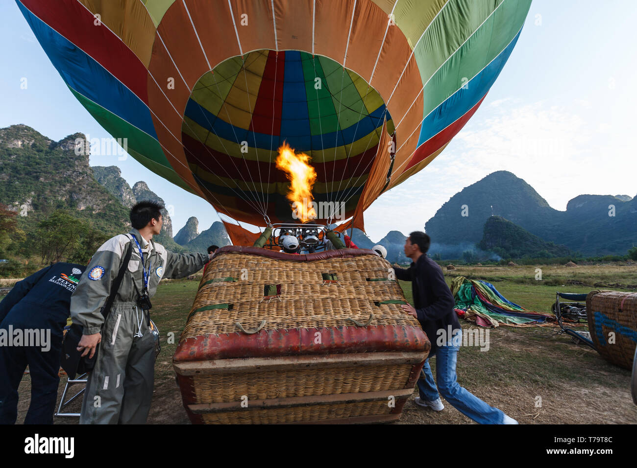 Workers tip basket so people can climb in a hot air balloon for a ride over the Yangshao Valley and mountains Stock Photo