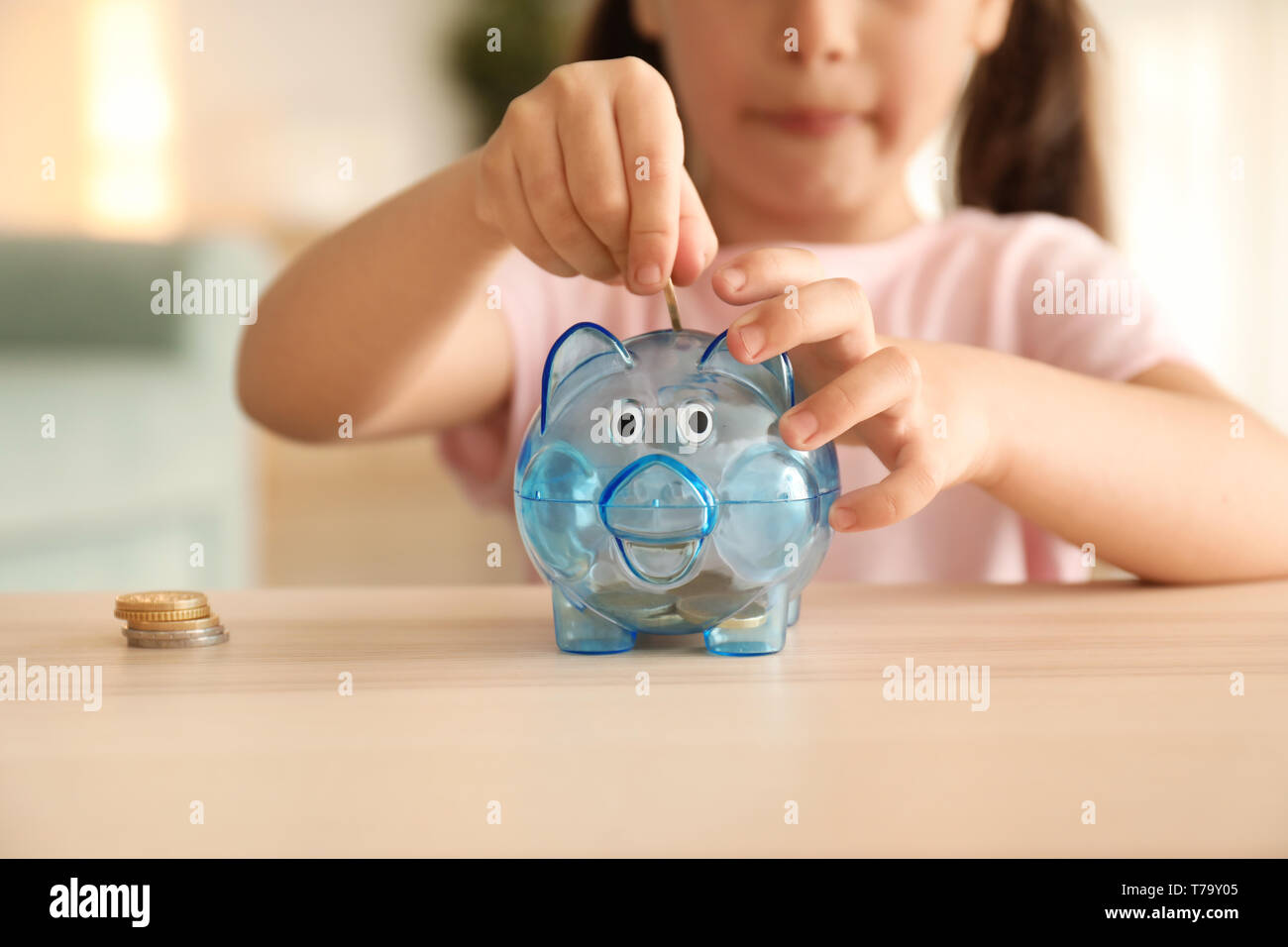Little girl putting coins into piggy bank indoors. Money savings ...