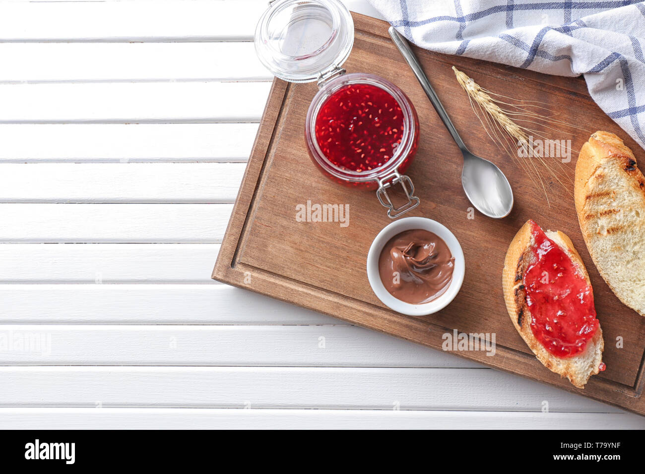 Toasted bread with jam and chocolate paste on wooden board Stock Photo ...