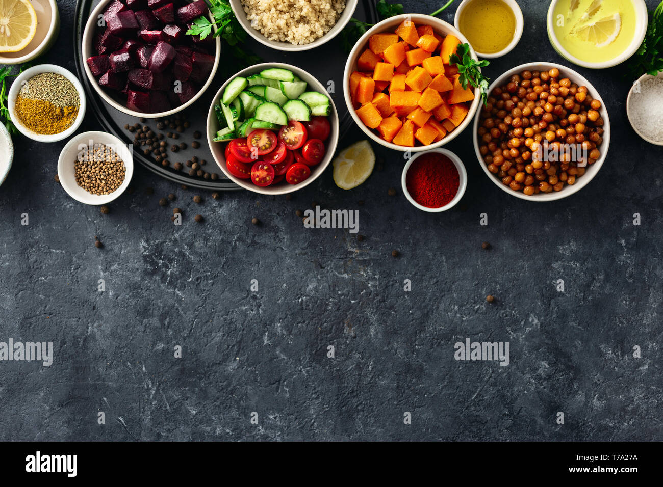 Set food for cooking healthy vegetarian food. Spiced chickpeas, baked pumpkin and beets, quinoa and vegetables on dark stone background with copy spac Stock Photo