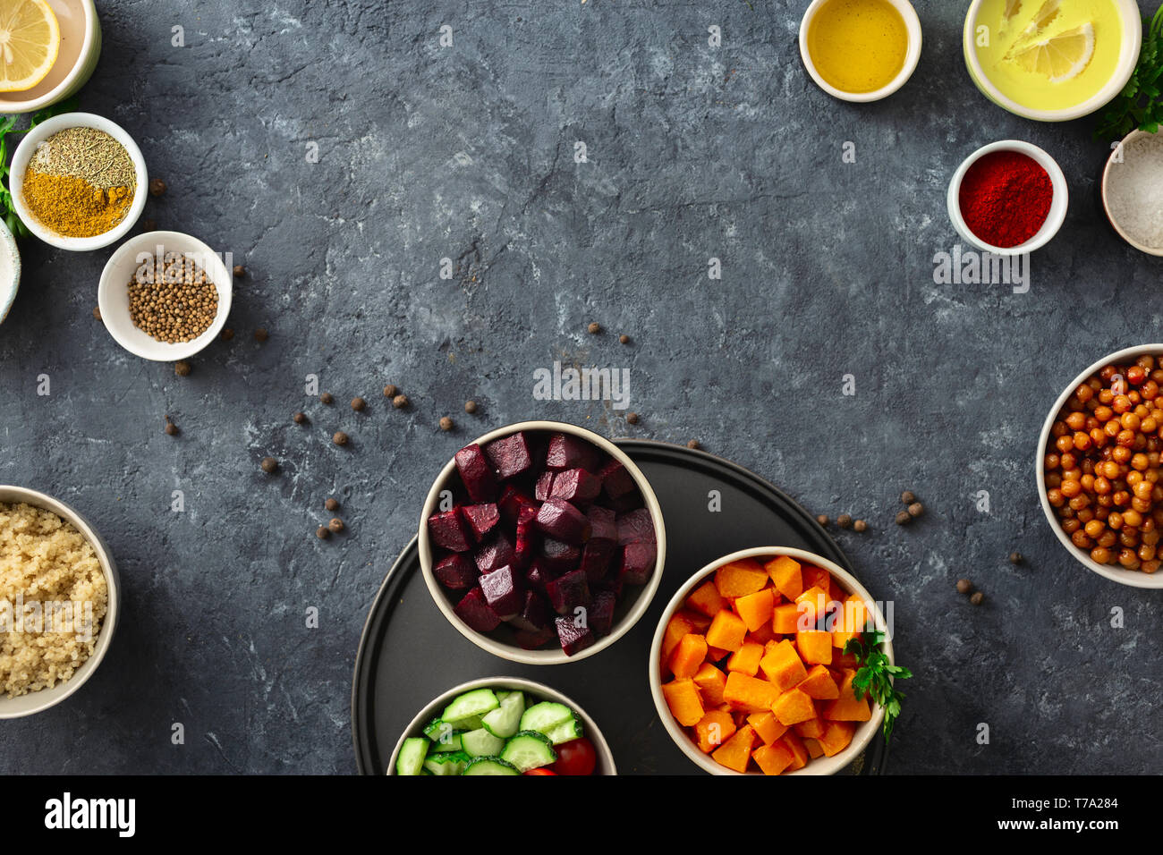 Set food for cooking healthy vegetarian food. Spiced chickpeas, baked pumpkin and beets, quinoa and vegetables on dark stone background with copy spac Stock Photo